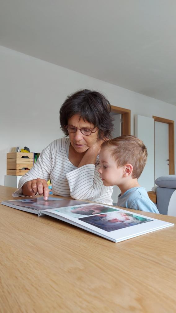 Foto van thuisbegeleider die samen met kind in boek kijkt